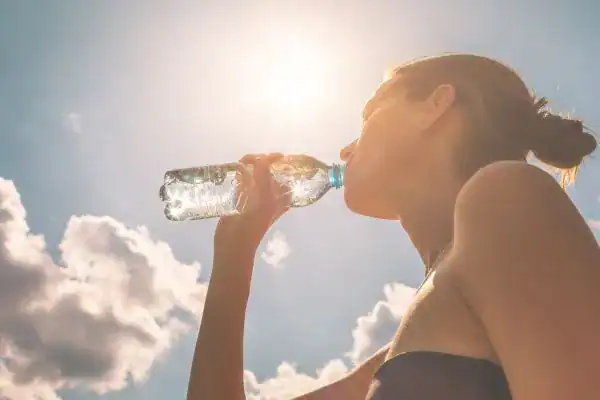Image of woman drinking water to hydrate Hampshire after run.
