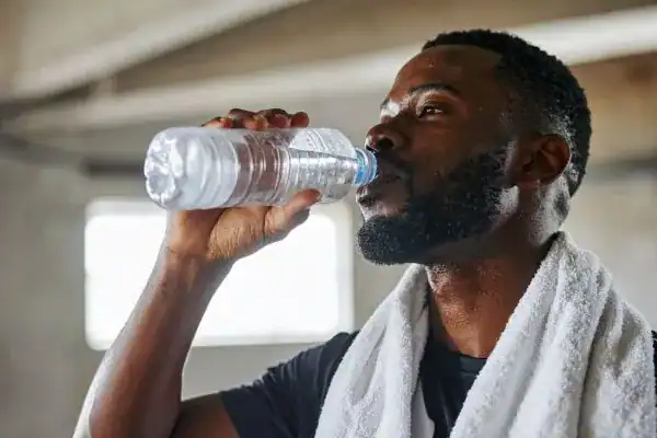Image of man drinking water to improve hydration Hampshire after work out.